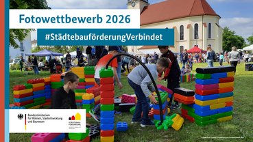Kinder bauen aus großen bunten Bausteinen eine Stadt.